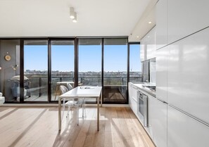 Eine moderne Küche mit großem Fenster, einem Essbereich mit Tisch und Stühlen sowie Blick auf die Stadtlandschaft.