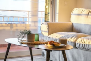 A cozy room with a sofa, a small table with a plant, a plate with food, and a glass of beverage. - Villa with stunning Ocean Views & Priv. Heated Pool (Luz)