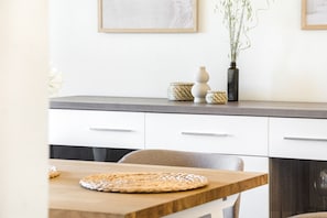 A modern kitchen with a wooden table, white cabinets, and decorative items on the countertop. - Villa with stunning Ocean Views & Priv. Heated Pool (Luz)