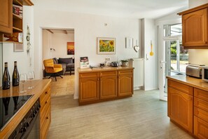 Una cocina moderna con armarios de madera, horno empotrado y zona de comedor con sofá y mesa.