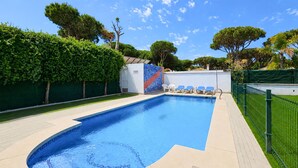 A swimming pool with a tiled edge, a lounge area with chairs, and a green fence surrounding the area. - 4 bedroom lovely home in Roche (Roche)