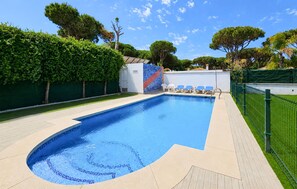 A swimming pool with a tiled edge, a lounge area with chairs, and a green fence surrounding the area. - 4 bedroom lovely home in Roche (Roche)