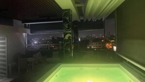 A modern interior with a green-lit jacuzzi, large windows offering city views, and a minimalist design. - Paradise paradise oasis private jacuzzi (Santo Domingo)