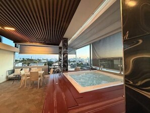 Eine Dachterrasse mit Whirlpool, Sitzgelegenheit und Blick auf die Stadt.