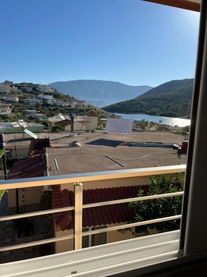 Uma varanda com vista para uma cidade costeira, montanhas e um corpo de água.
