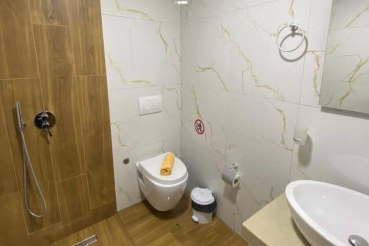 A bathroom with a shower, toilet, sink, and a mirror.