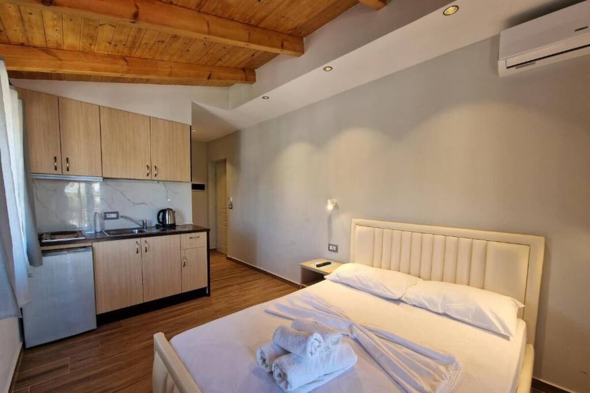 A hotel room with a bed, a small kitchenette, and a wooden ceiling.