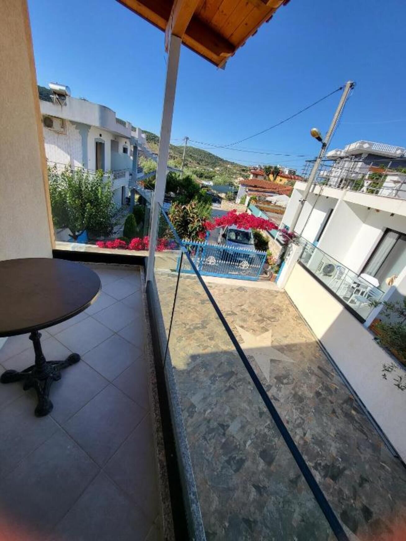 Un balcone con vista su una zona residenziale, un tavolo e una recinzione blu.