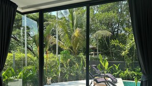 Ein modernes Zimmer mit einem großen Schiebeglastür, die zu einem privaten Außenbereich mit Pool und Liegestühlen führt.
