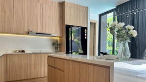 Eine moderne Küche mit Holzschränken, einem eingebauten Herd und einem großen Fenster mit Blick auf Grünflächen.