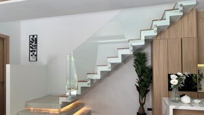 Eine moderne Treppe mit Glastrennwand, einem Blumentopf und einem kleinen Tisch mit Dekoration.