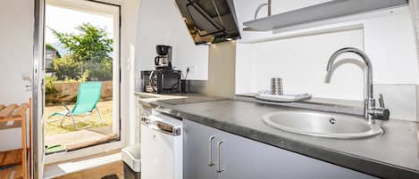 Una cocina compacta equipada con microondas, un lavamanos y una cafetera.