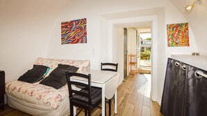 A room with a bed, a table, chairs, a kitchen area, and two abstract paintings. - 1 bedroom amazing apartment in Moriani-Plage (Moriani-Plage)
