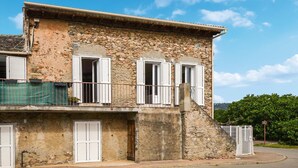A two-story stone building with white shutters, a balcony, and a gated entrance. - 1 bedroom amazing apartment in Moriani-Plage (Moriani-Plage)