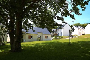 Un barrio residencial con casas, un árbol y un césped.
