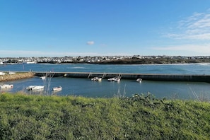 A coastal view with a marina, boats, and a distant town. - Duplex Cottage for 4 in Audierne (Audierne)