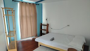 A bedroom with a wooden bed, a wooden ladder, a window with curtains, and a wall socket. - Blu Corner - a place to relax (Lian)
