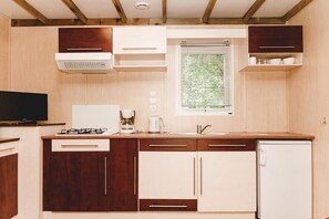 A compact kitchen with a gas stove, a coffee maker, and a refrigerator.