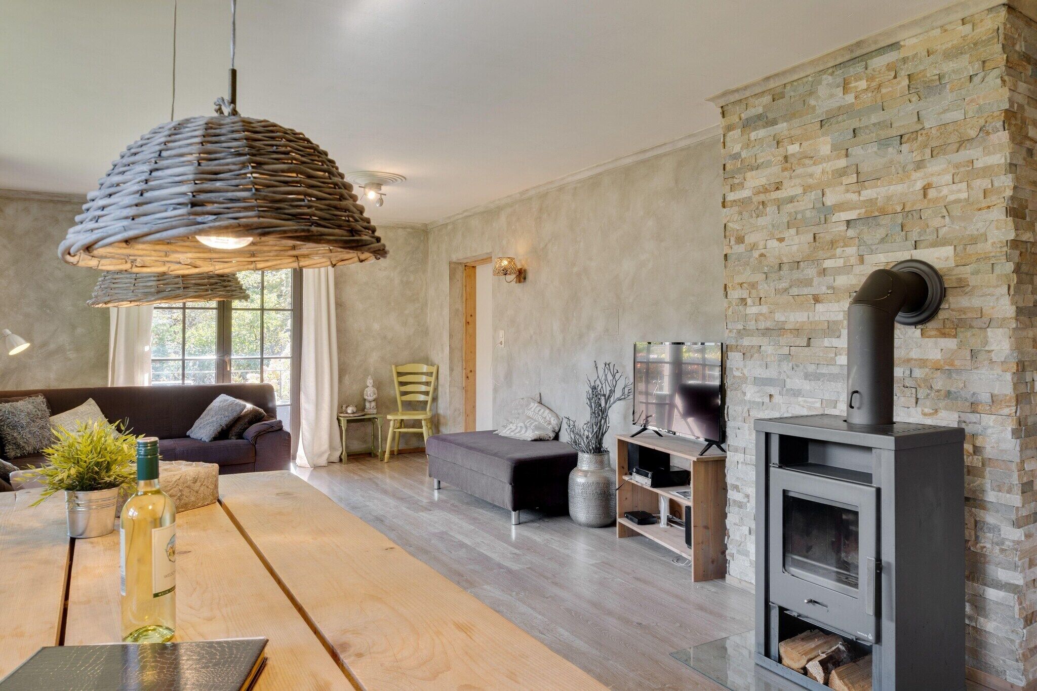 Ein modernes Wohnzimmer mit Steinwand, Kamin, einer Couch, einem Esstisch und einer Pendelleuchte.