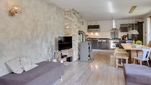 Uma sala de estar moderna com parede de destaque em pedra, uma TV de tela plana e um sofá.