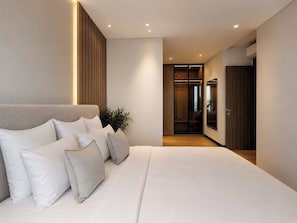 Ein modernes Schlafzimmer mit einem großen Bett, einer Zimmerpflanze und einem begehbaren Kleiderschrank.