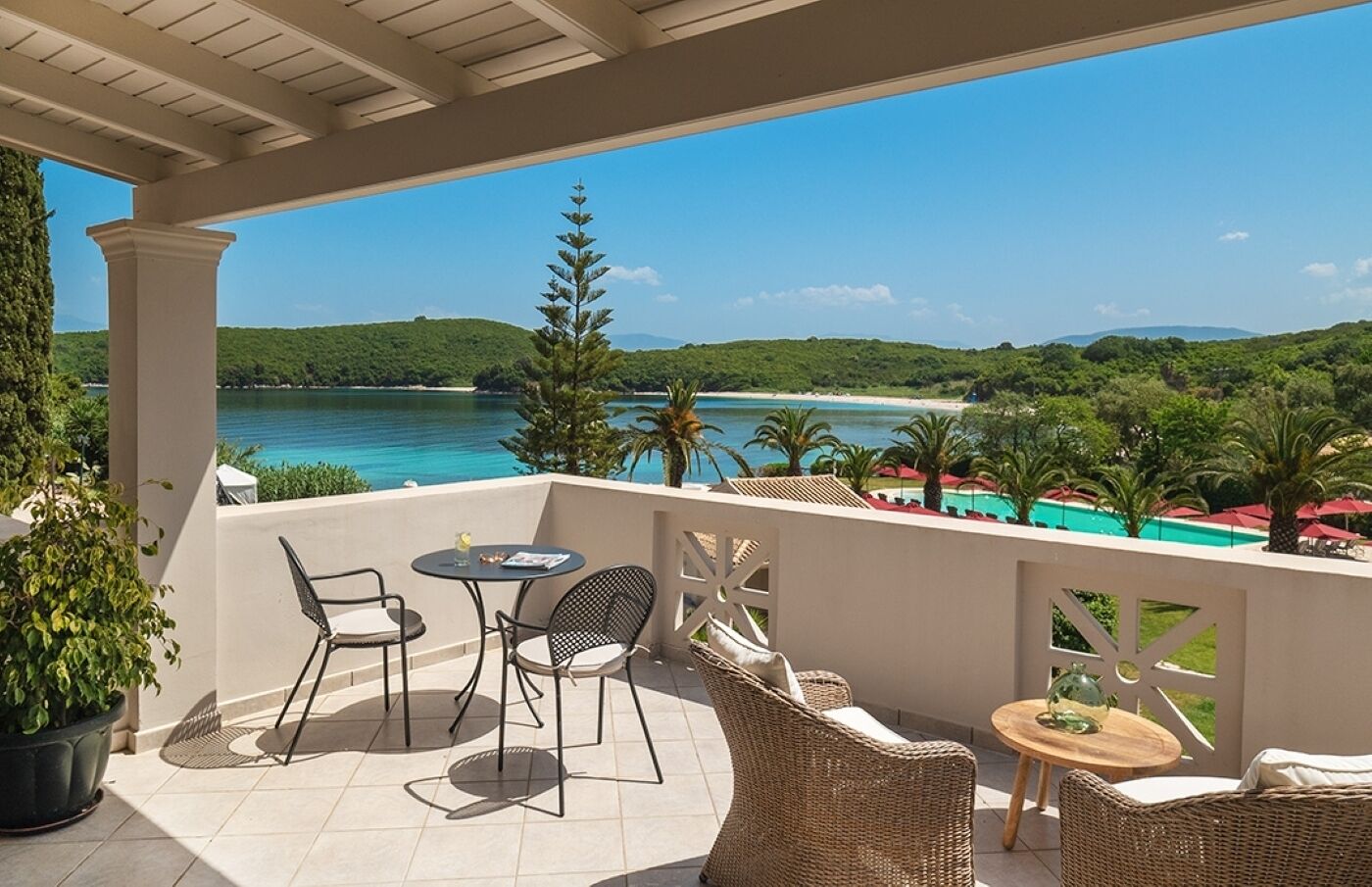 Un espace extérieur abrité, offrant une vue sur la plage et les montagnes, et aménagé avec des chaises et des tables en osier.