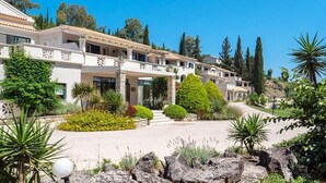 A multi-story hotel with a central courtyard, surrounded by landscaped gardens and trees. - Bella Mare Hotel (Corfu)