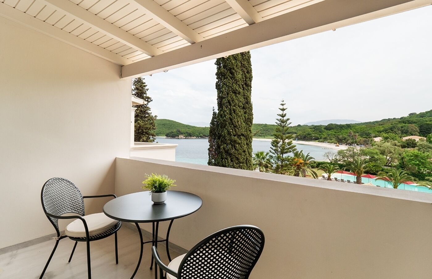 A balcony with a table and chairs, overlooking a scenic view of a body of water and greenery.