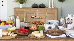 A breakfast buffet with various food items, a wooden cabinet, and decorative plants. - Bella Mare Hotel (Corfu)