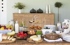 Un ricco buffet della colazione con diversi cibi, un mobile in legno e piante decorative.
