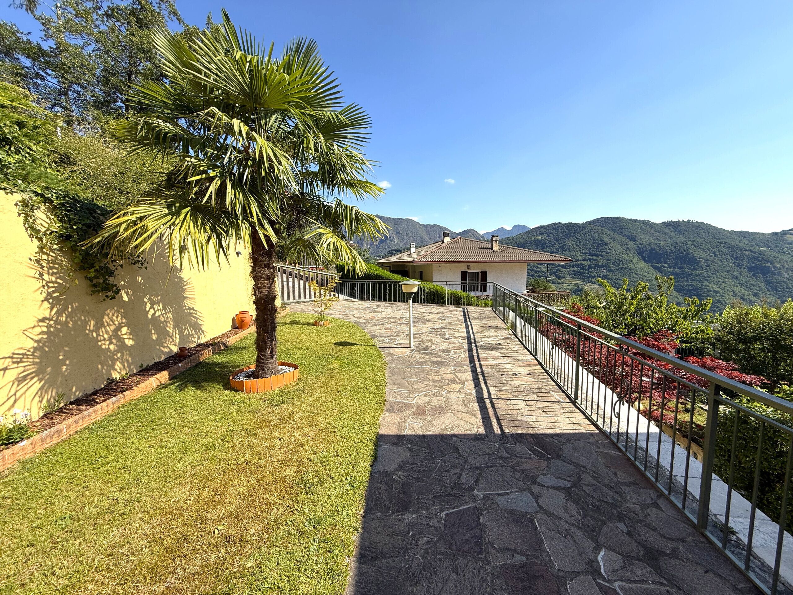 A stone pathway leading to a house with a mountain backdrop.