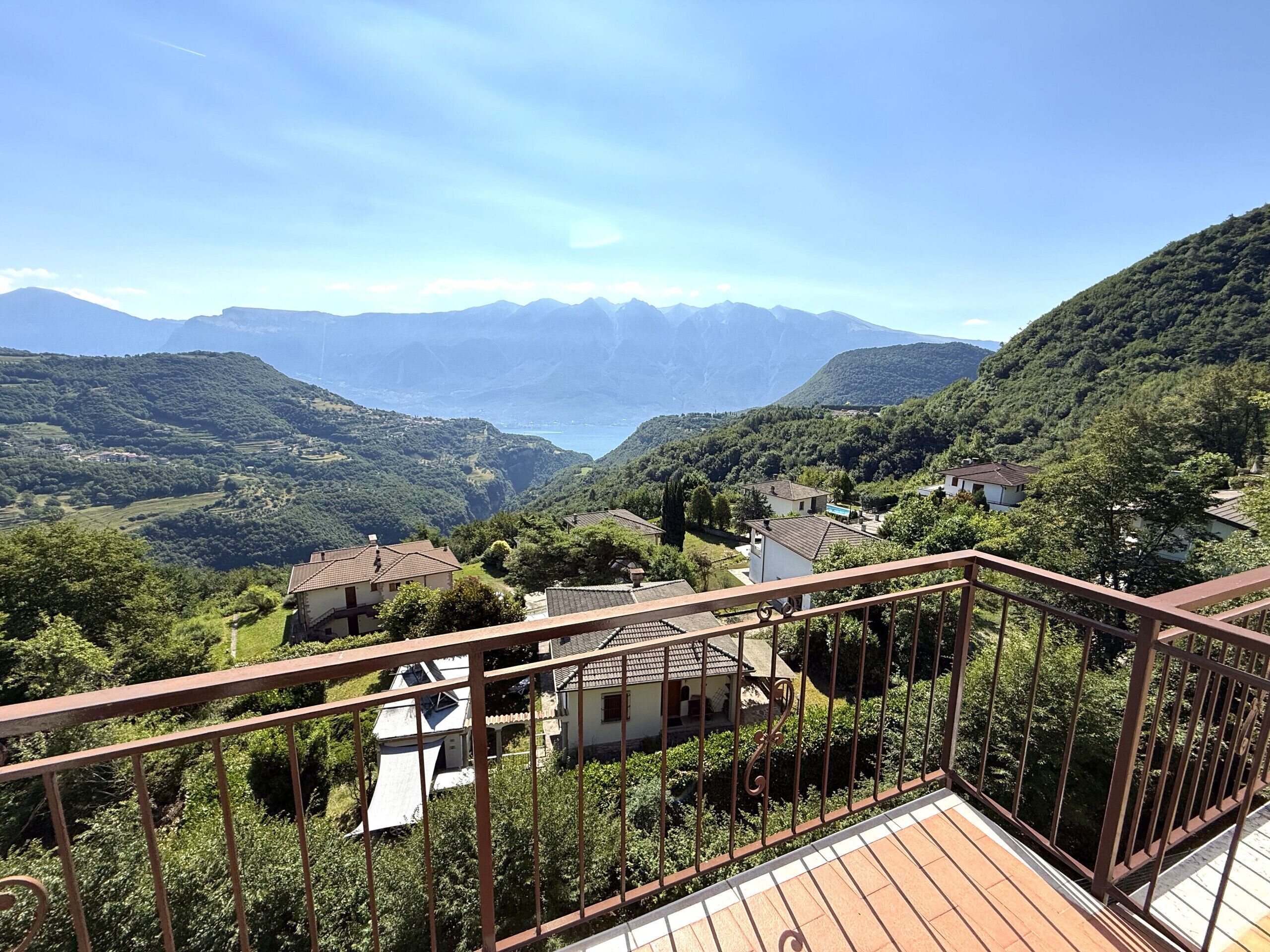 A balcony with a view of a valley, houses, and mountains.