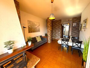 Ein modernes Wohnzimmer mit einer Couch, einem Esstisch mit Stühlen, einer Treppe und einem Küchenbereich.