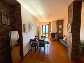 A spacious living area with a fireplace, a dining table with chairs, and a sofa. - Ammura Apartment: Balcony, Garden (Tignale)