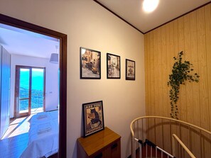 Ein Zimmer mit einem Bett, einer Holzbank, einer Treppe und einer Wand mit gerahmten Bildern.