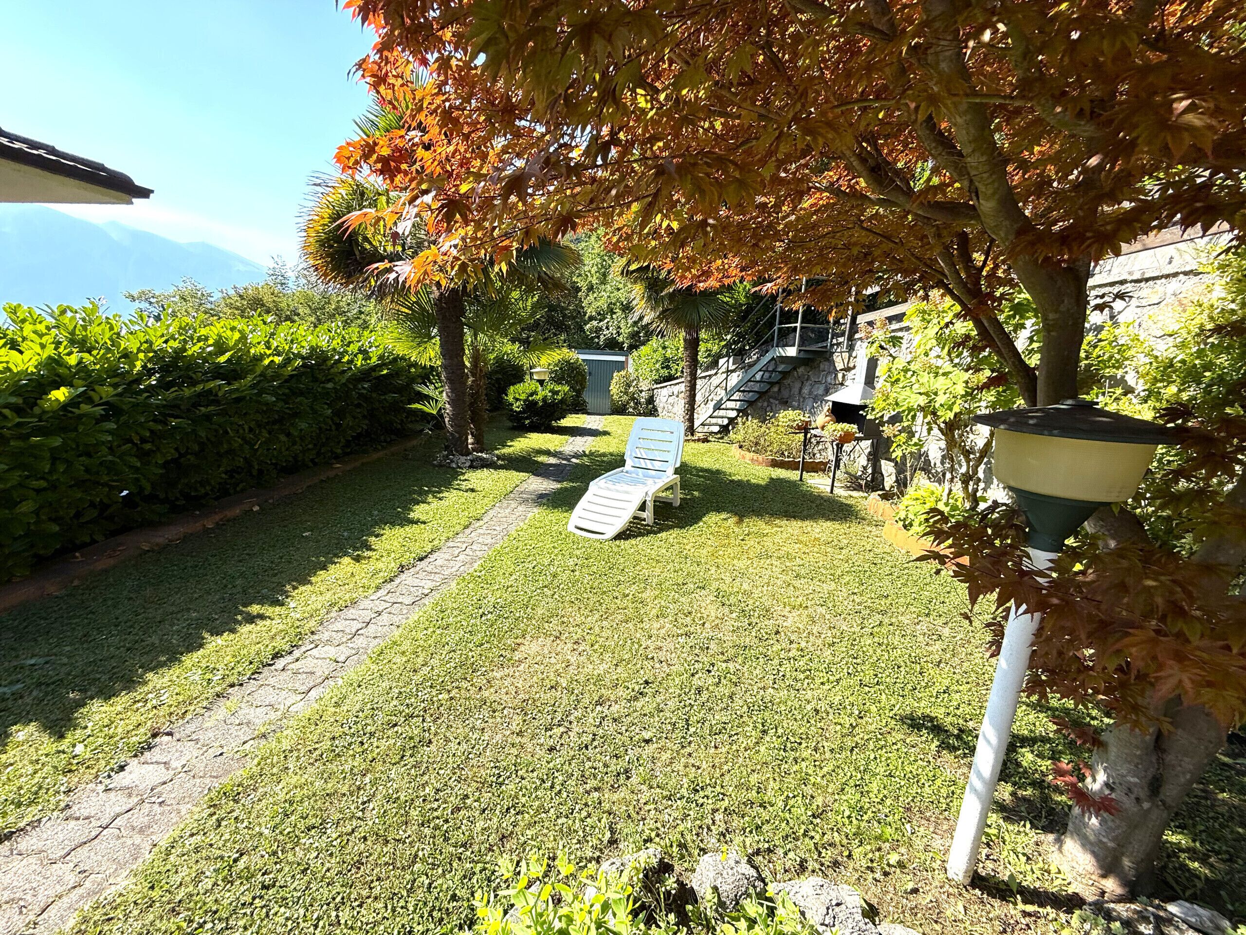 Ein gepflegter Garten mit Rasen, einem Weg und einem Stuhl.