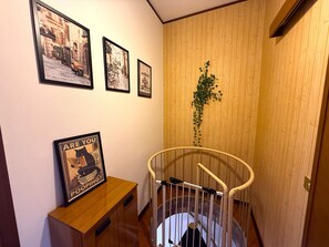 A staircase with a wooden railing, a wall-mounted plant, and framed pictures on the wall. - Apartment House Ammura Balcony Garden (Tignale)