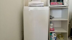 A compact room with a white washing machine, a microwave, and a shelf with toiletries. - LunaStay Apartments - 101 (Sumida-ku)