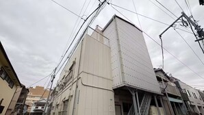 A multi-story building with a white facade, visible electrical infrastructure, and a staircase leading to an upper level. - LunaStay Apartments - 101 (Sumida-ku)