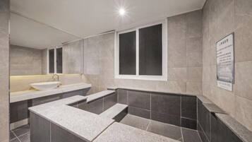 Un baño moderno con lavamanos, espejo y ventana.