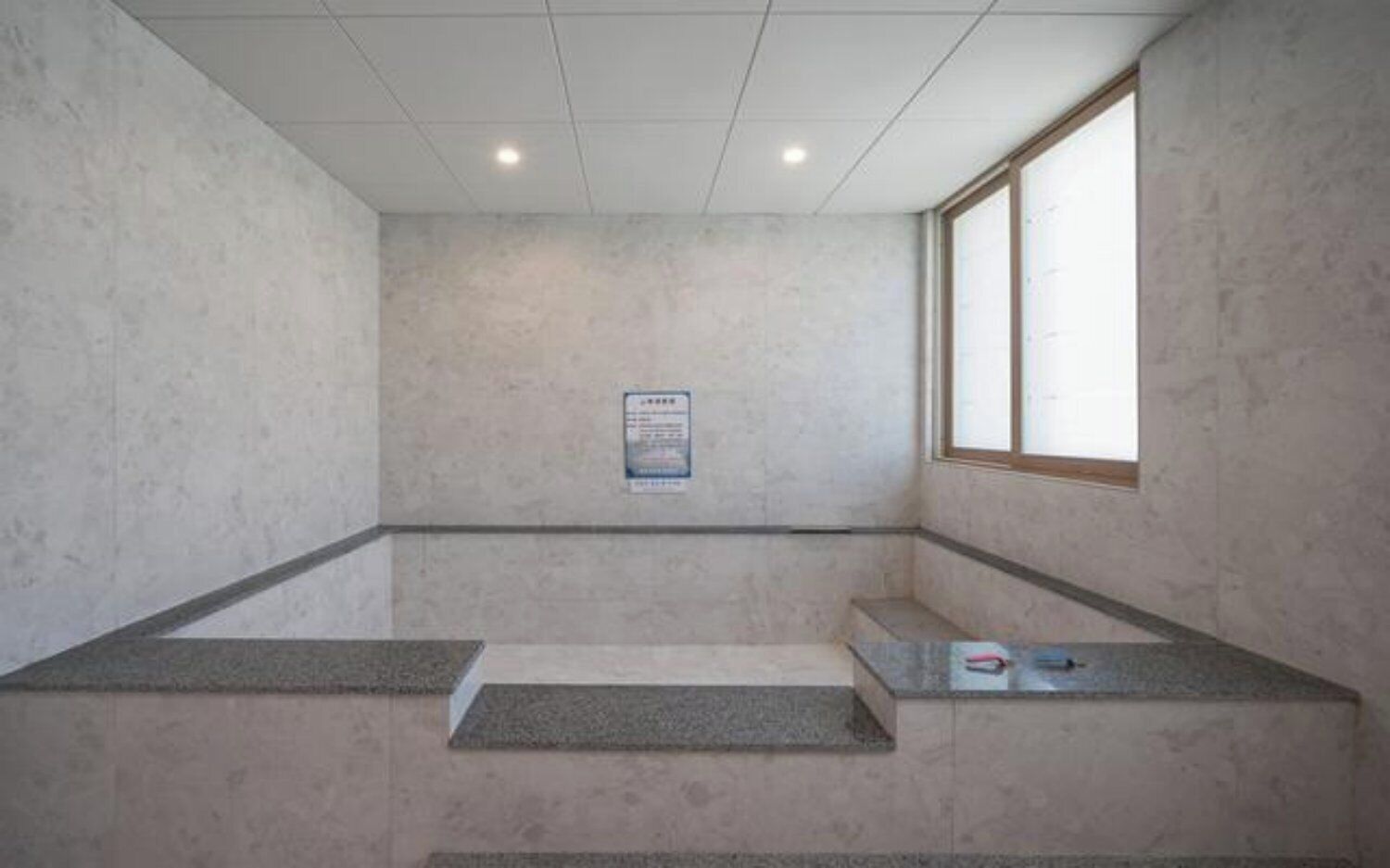 A room with a tiled floor, a window, and a sign on the wall.