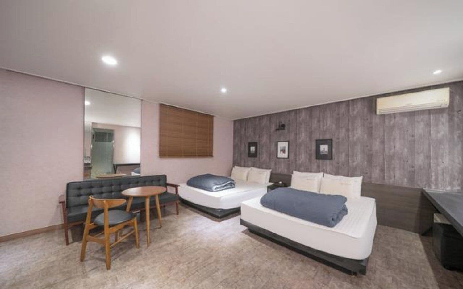 A hotel room with two beds, a sofa, a small table, and a mirror.