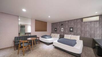 A hotel room with two beds, a sofa, a small table, and a mirror.