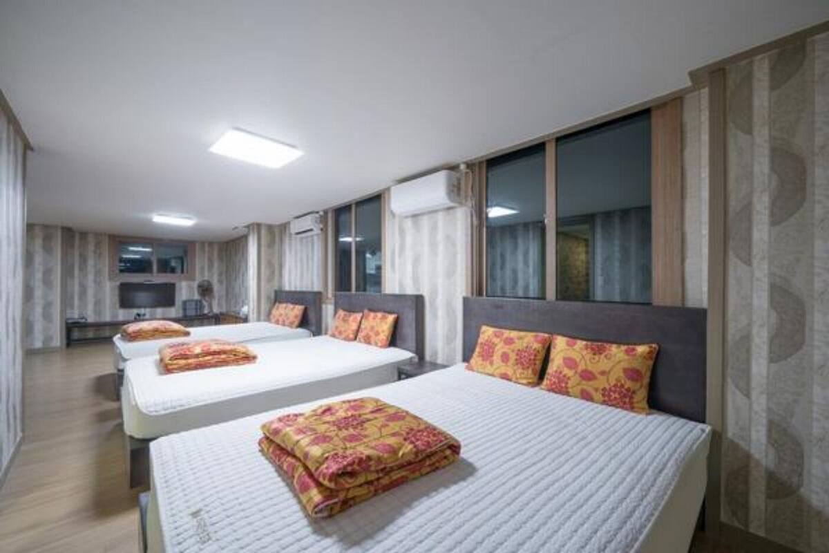Habitación de hotel con tres camas, un televisor de pantalla plana y un ventanal grande.
