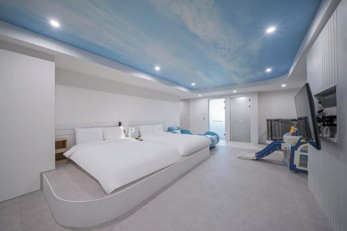 Una habitación de hotel moderna con una cama grande, televisión y un espacio de juegos para niños.