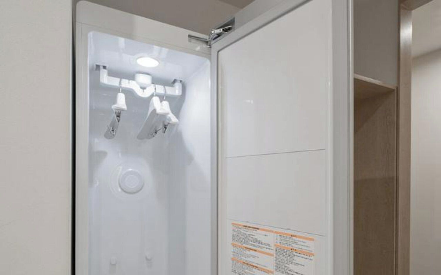 A white bathroom with a shower, a mirror, and a sign with text.