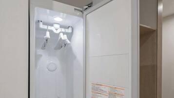A white bathroom with a shower, a mirror, and a sign with text.