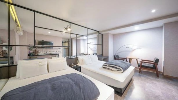 A modern hotel room with a large bed, a desk, and a chair.