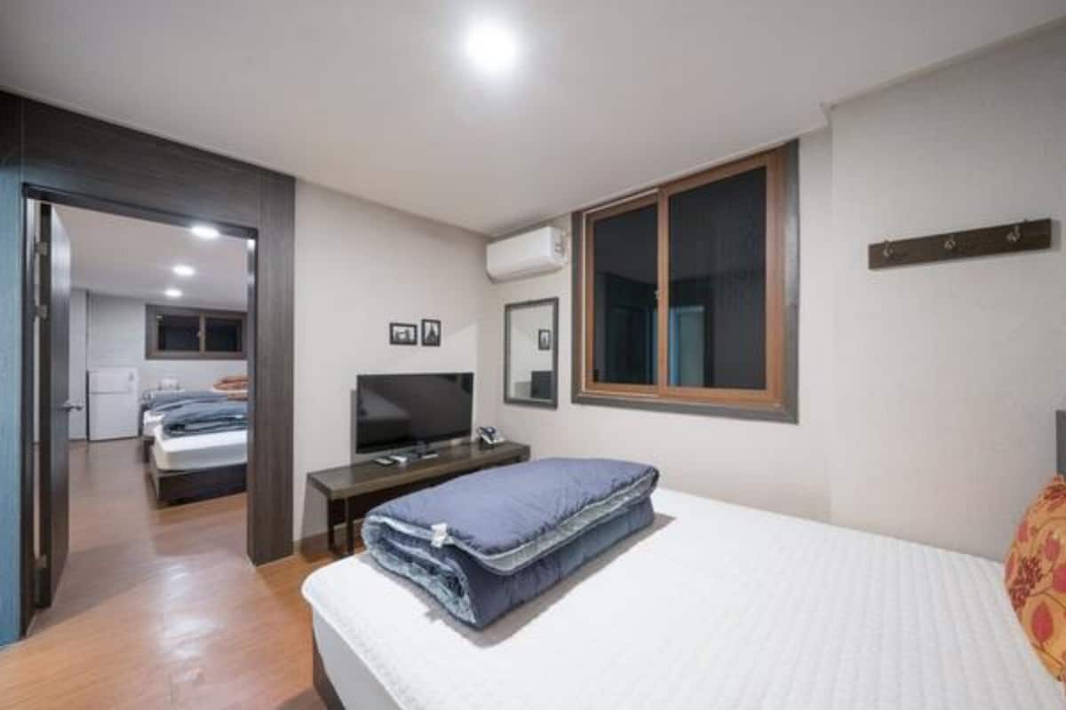 Un dormitorio con cama, televisión, ventana y puerta que da a un baño.