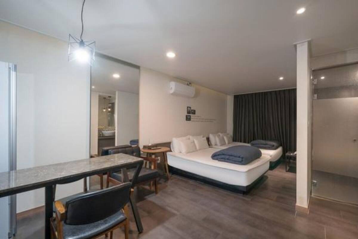 Una habitación de hotel moderna con comedor, sofá cama y dormitorio independiente.